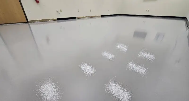 White solid color epoxy floor with a black cove base
