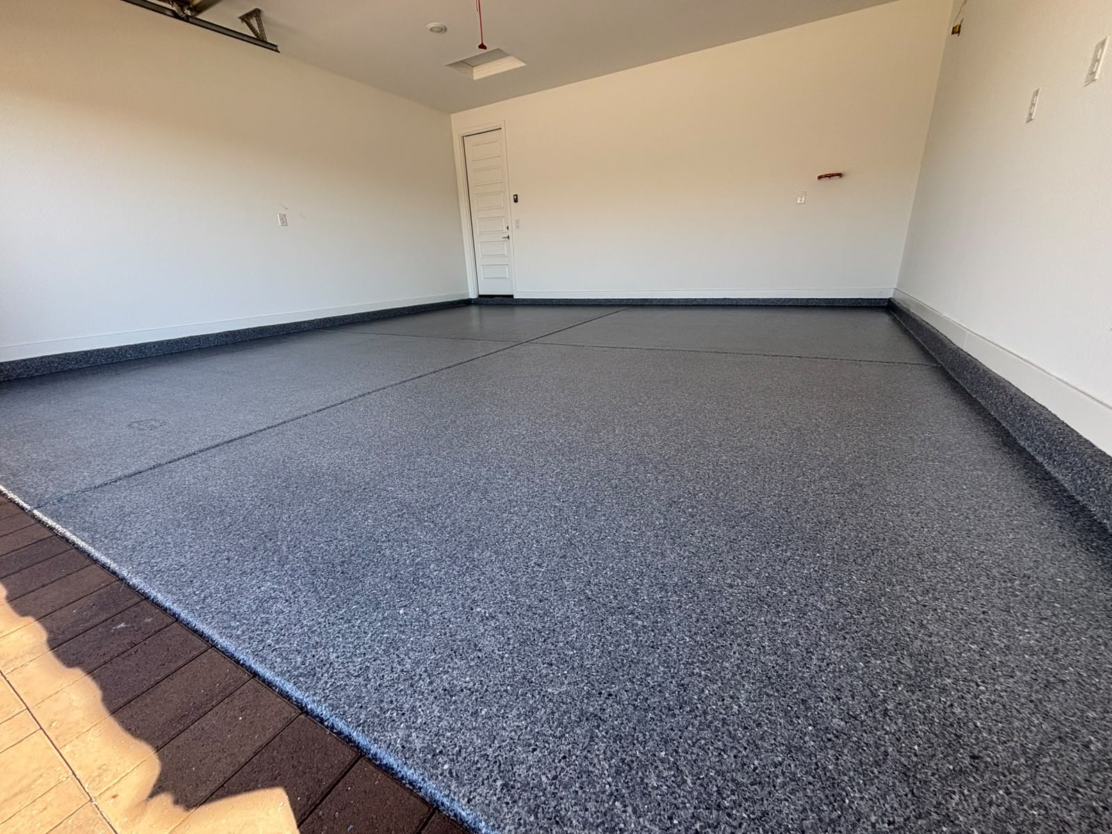 Dark grey flake epoxy garage floor with a cove base